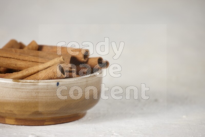 Cinnamon sticks in a ceramic bowl in different angles on white background