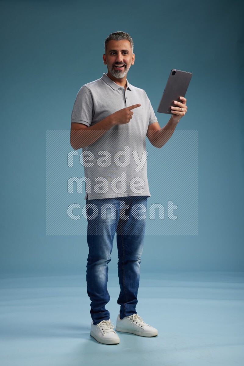 Man Standing working on tablet on blue background