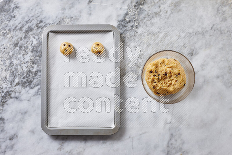 Cookies step by step with its ingredient, flour, butter, brown sugar, egg, vanilla extract, white sugar, chocolate chips and baking soda on grey marble background