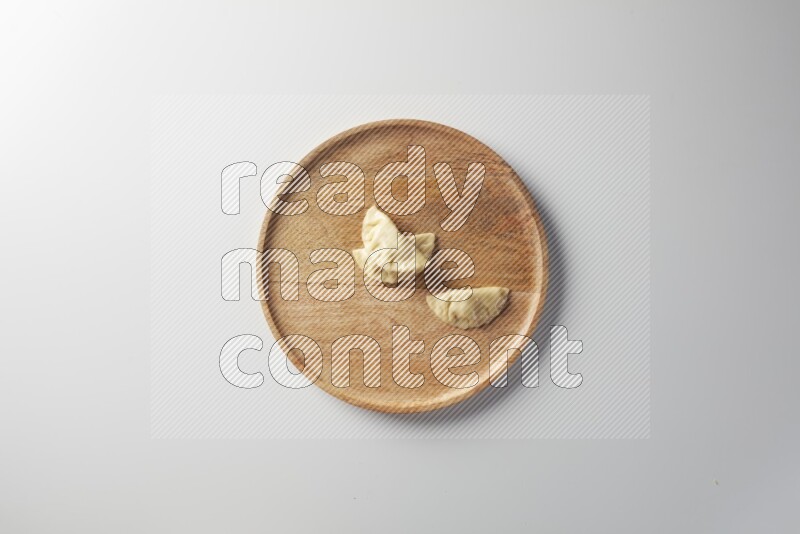 Three Sambosas on a wooden round plate on a white background