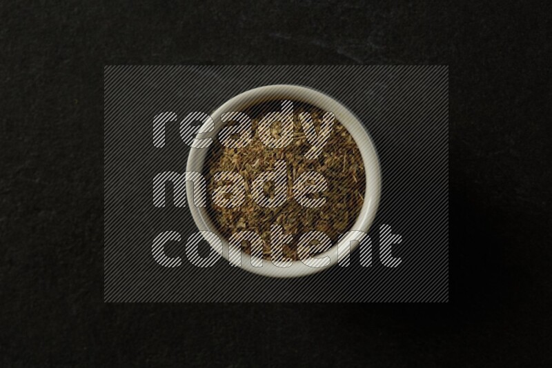 white ceramic round sauce bowl filled with herbs on grey textured countertop