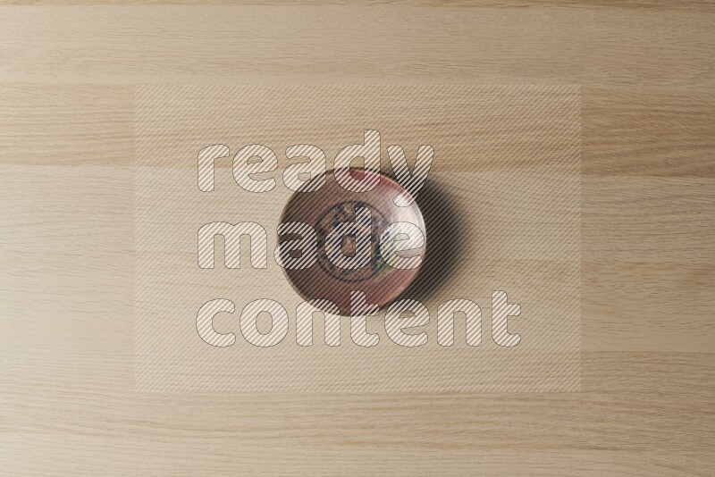 A decorative pottery plate on light wooden background