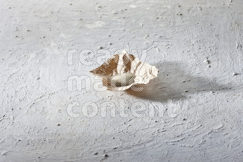 White pepper powder in a crumpled piece of paper on textured white flooring
