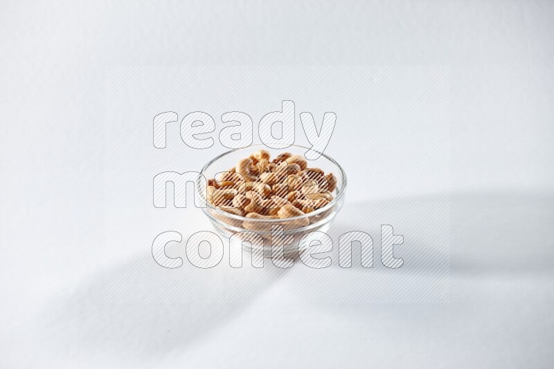 A glass bowl full of cashews on a white background in different angles