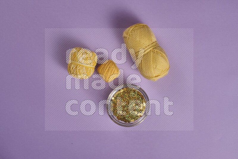 مجموعة من أدوات الخياطة والتفصيل صفراء وأرجوانية اللون على خلفية أرجوانية