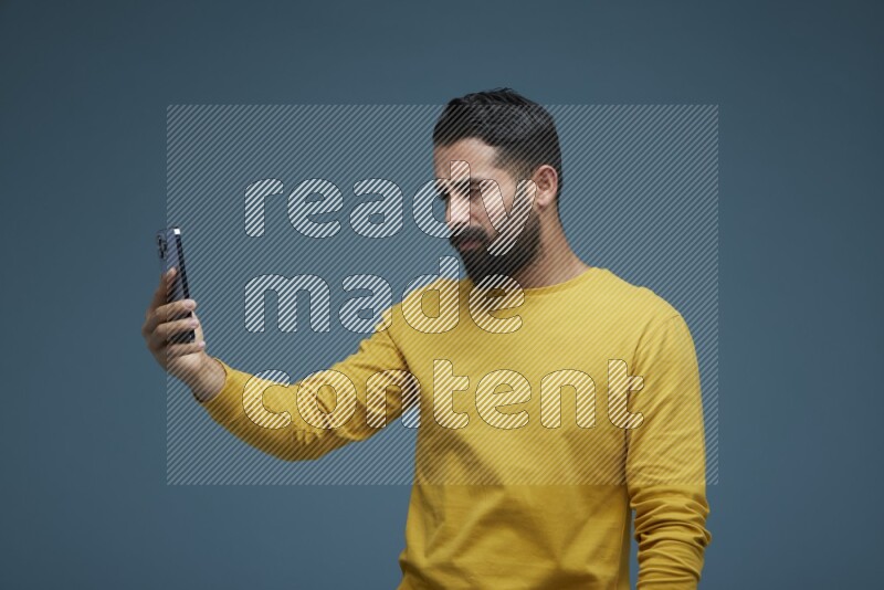 Man Taking a Selfie  in a blue background wearing a yellow shirt