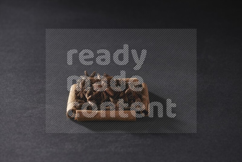 A single square of cinnamon sticks full of star anise on black flooring