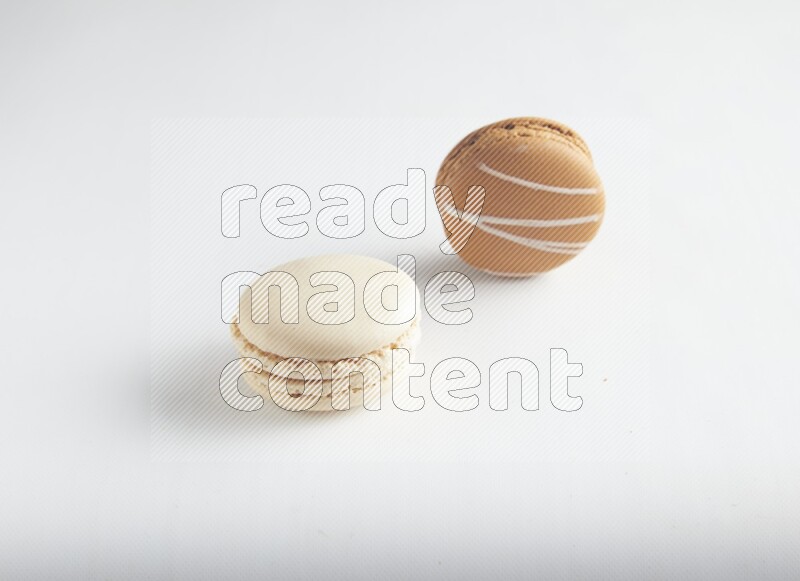 45º Shot of of two assorted Brown Irish Cream, and White Caramel fleur de sel macarons on white background