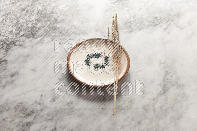 Wheat stalks on decorative pottery plate on grey marble background