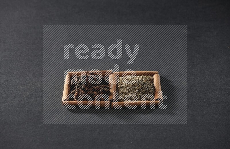 2 squares of cinnamon sticks full of cumin and star anise on black flooring