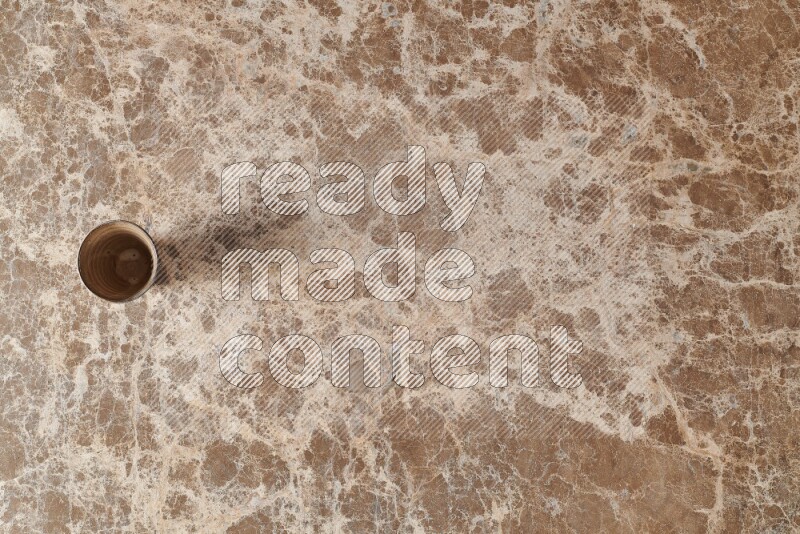 A pottery cup on beige marble background