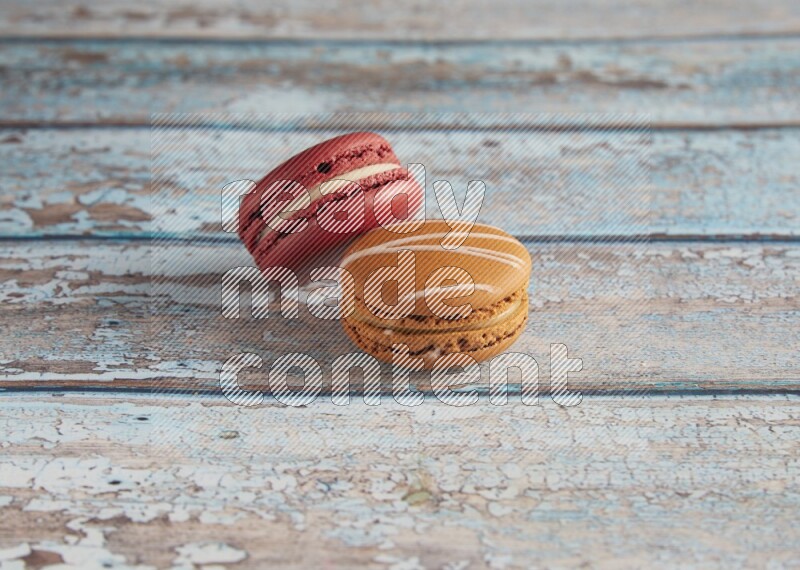 45º Shot of of two assorted Brown Irish Cream, and Red Velvet macarons on light blue background