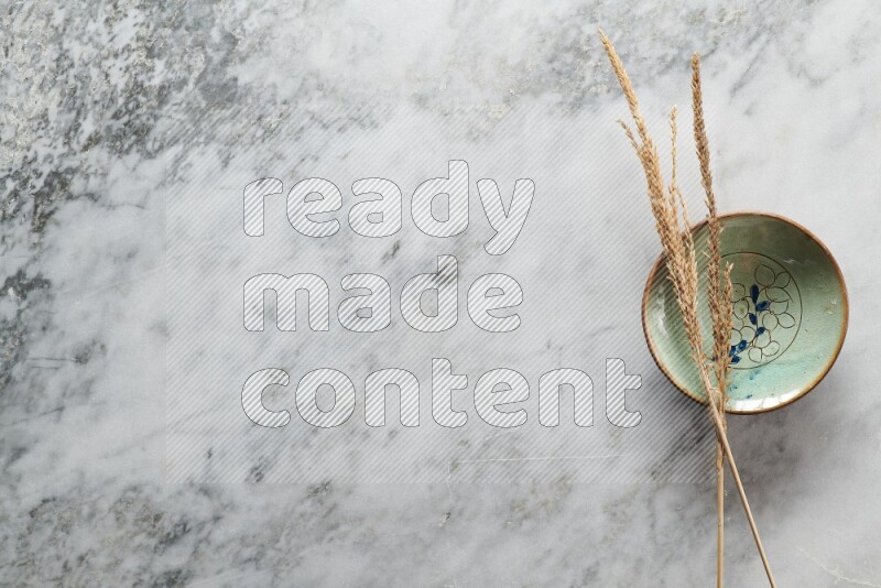 Wheat stalks on decorative pottery plate on grey marble background