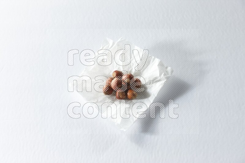 Hazelnuts on a crumpled piece of paper on a white background in different angles
