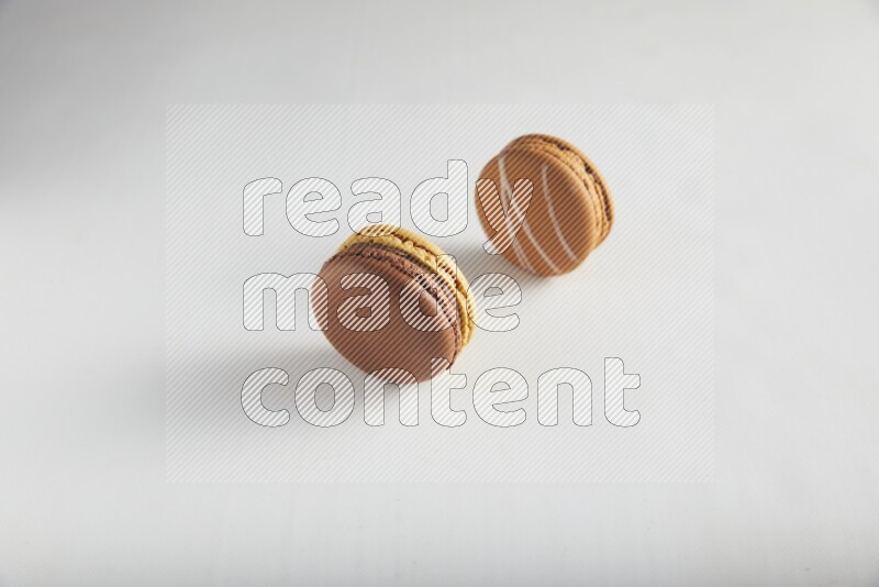 45º Shot of of two assorted Brown Irish Cream, and Yellow, and Brown Chai Latte macarons on white background