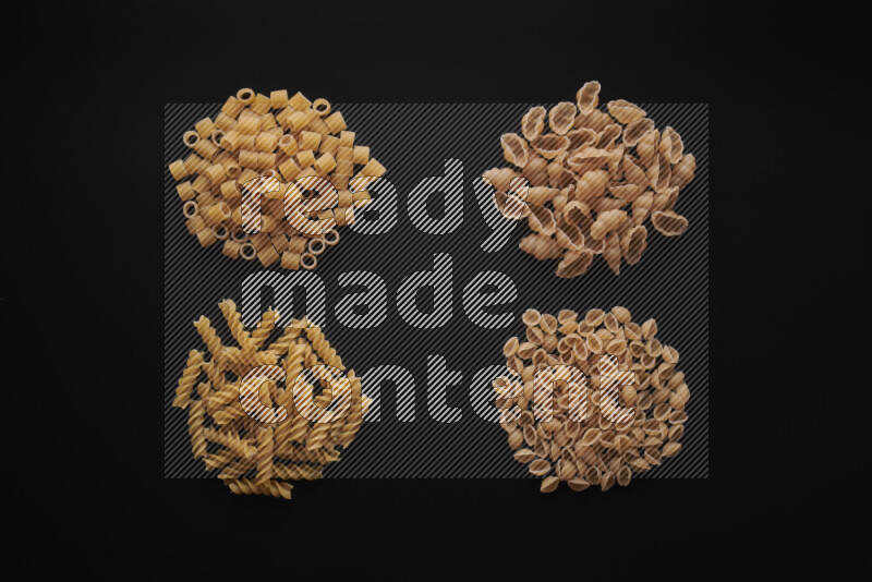 Different pasta types in bunches on black background