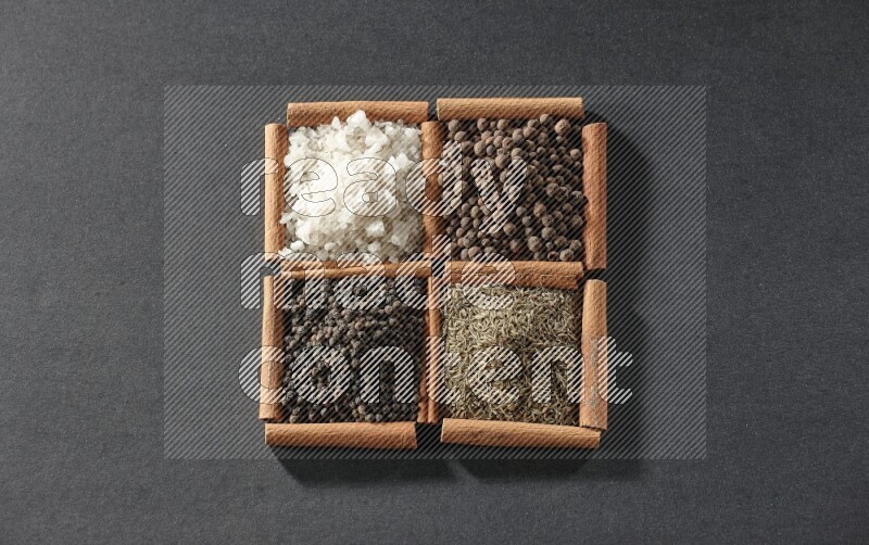 4 squares of cinnamon sticks full of black pepper, cumin, allspice and white salt on black flooring