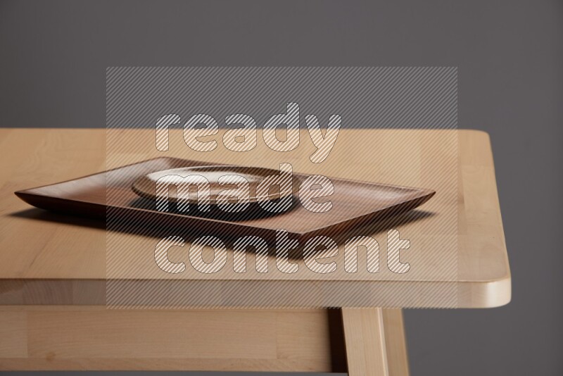 multicolored plate on a rectangular wooden tray on the edge of wooden table