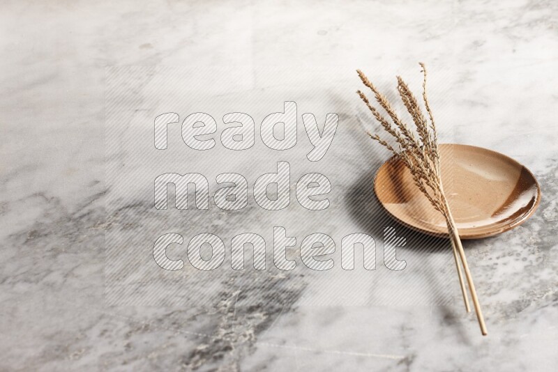Wheat stalks on multicolored pottery plate on grey marble background