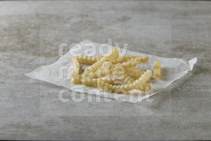 crinkle fries on parchment paper on grey textured counter top