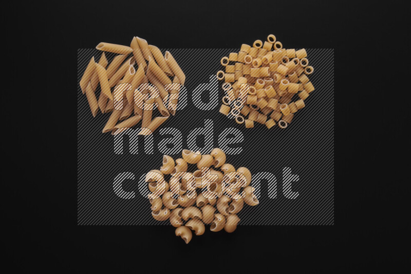 Different pasta types in bunches on black background