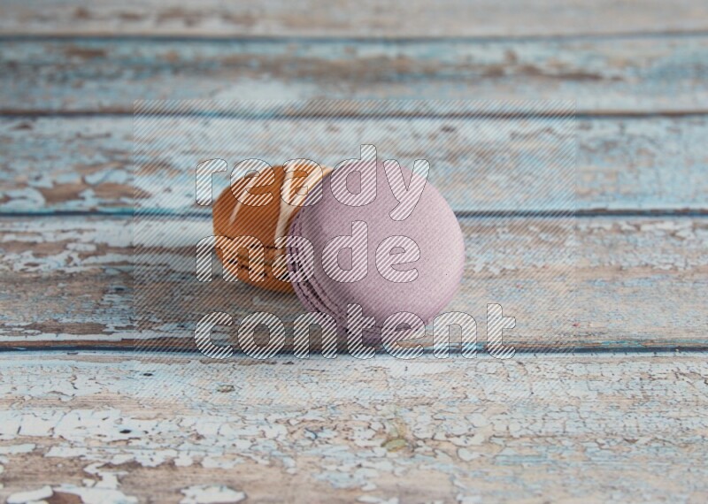 45º Shot of of two assorted Brown Irish Cream, and Purple Blueberry macarons  on light blue background