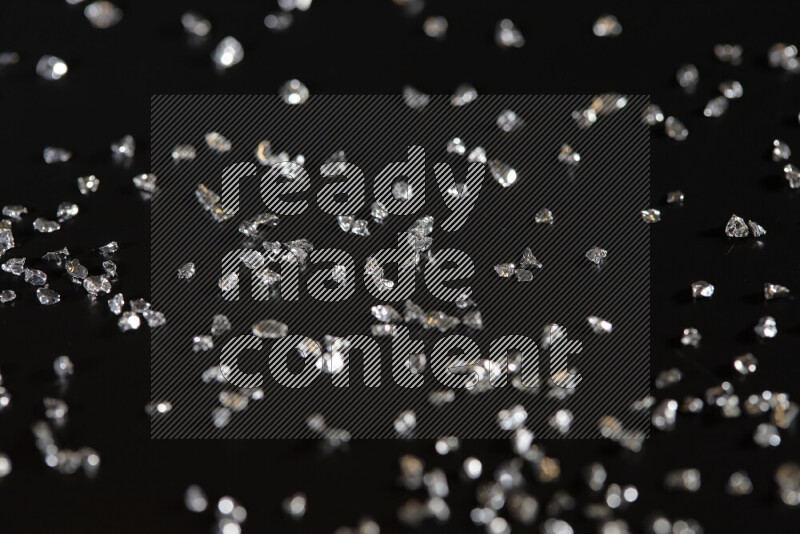 Silver shimmering fragments of glass scattered on a black background