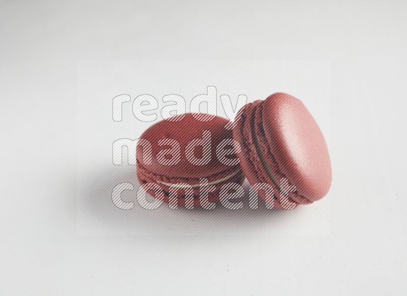 45º Shot of two Red Velvet macarons on white background