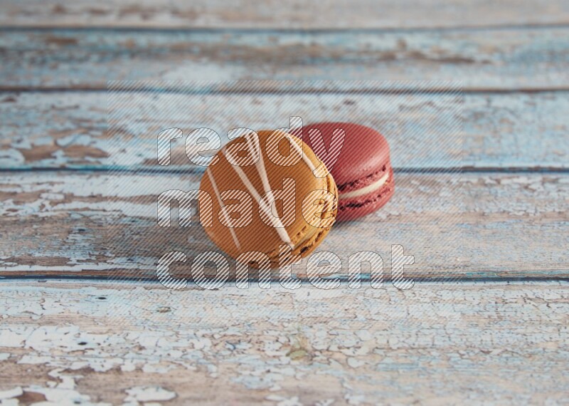 45º Shot of of two assorted Brown Irish Cream, and Red Velvet macarons on light blue background