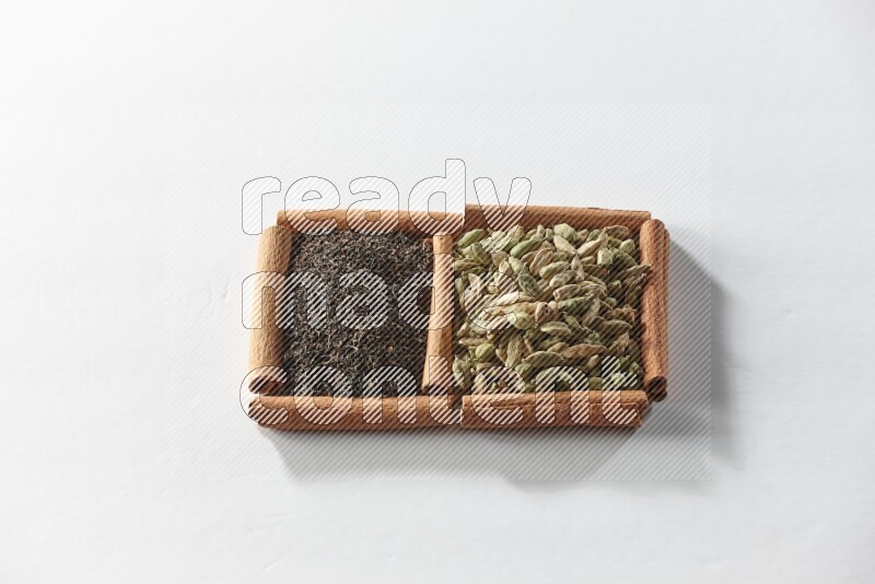 2 squares of cinnamon sticks full of cardamom and black tea on white flooring