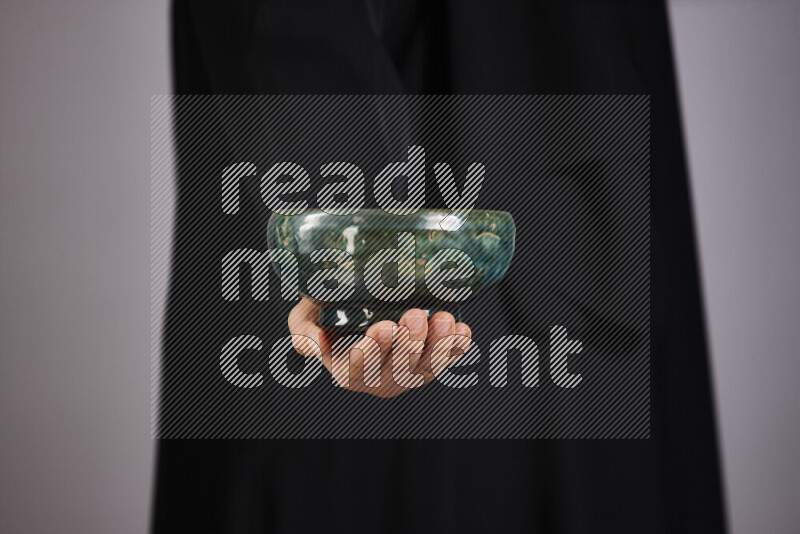 A woman in black abaya holding different pottery essentials in different positions