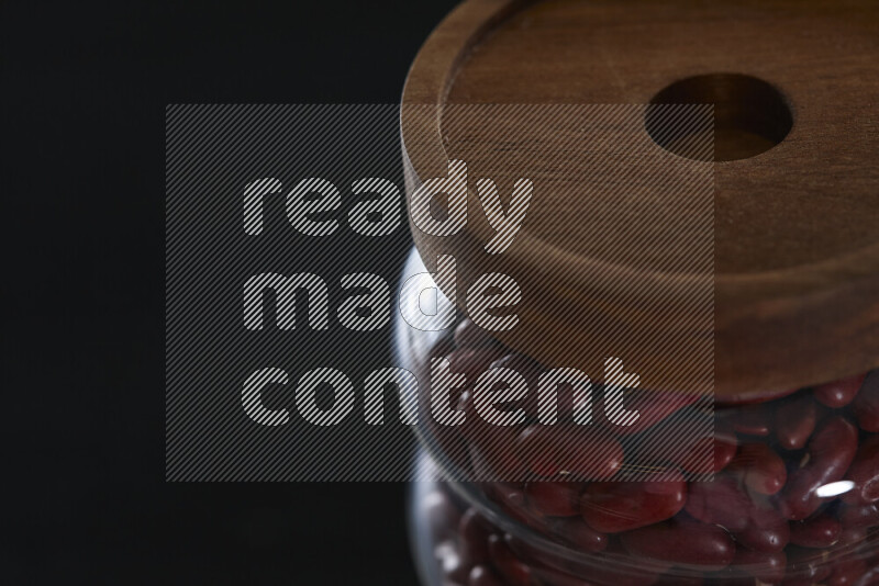 Red kidney beans in a glass jar on black background