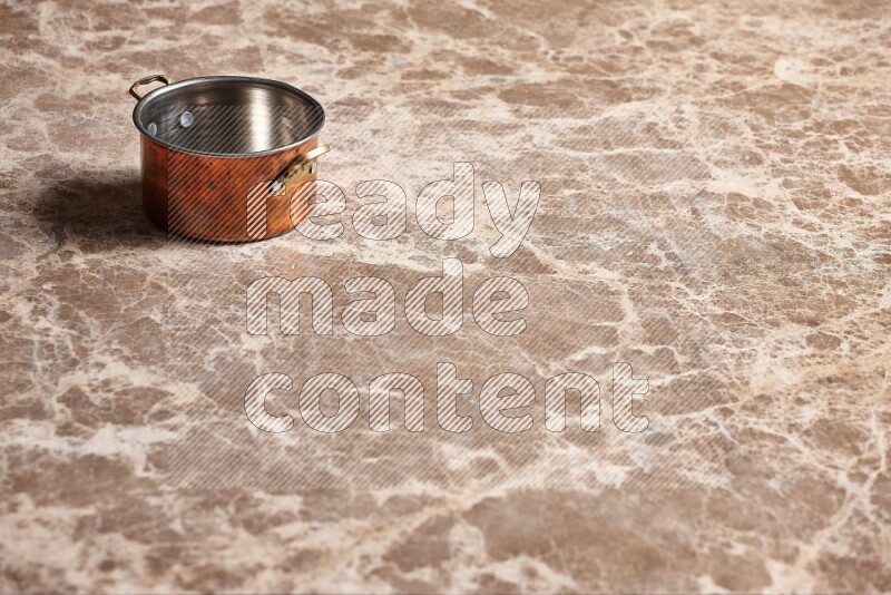 A small copper pot on beige marble background
