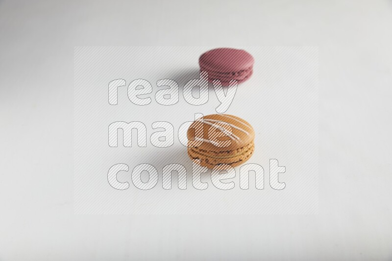 45º Shot of of two assorted Brown Irish Cream, and Red Cherry macarons on white background