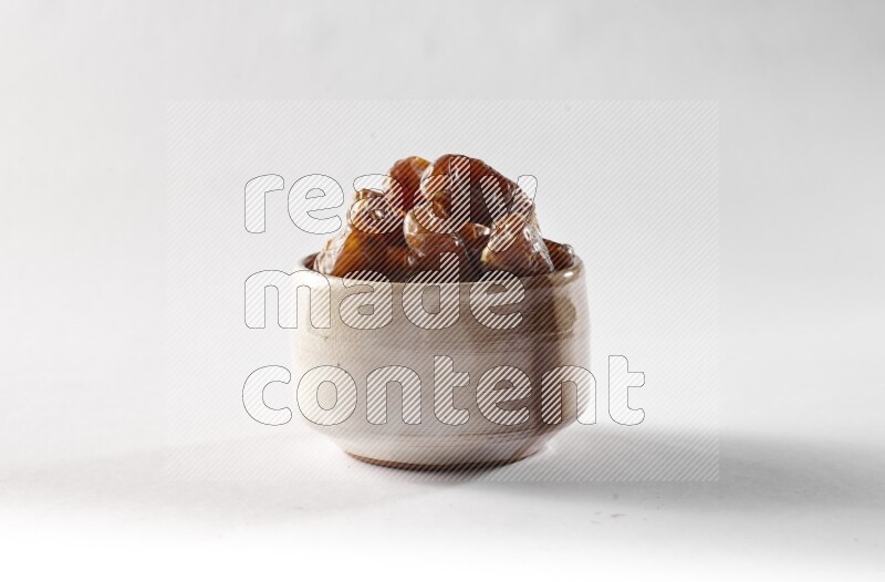 Dates in a beige pottery bowl on white background