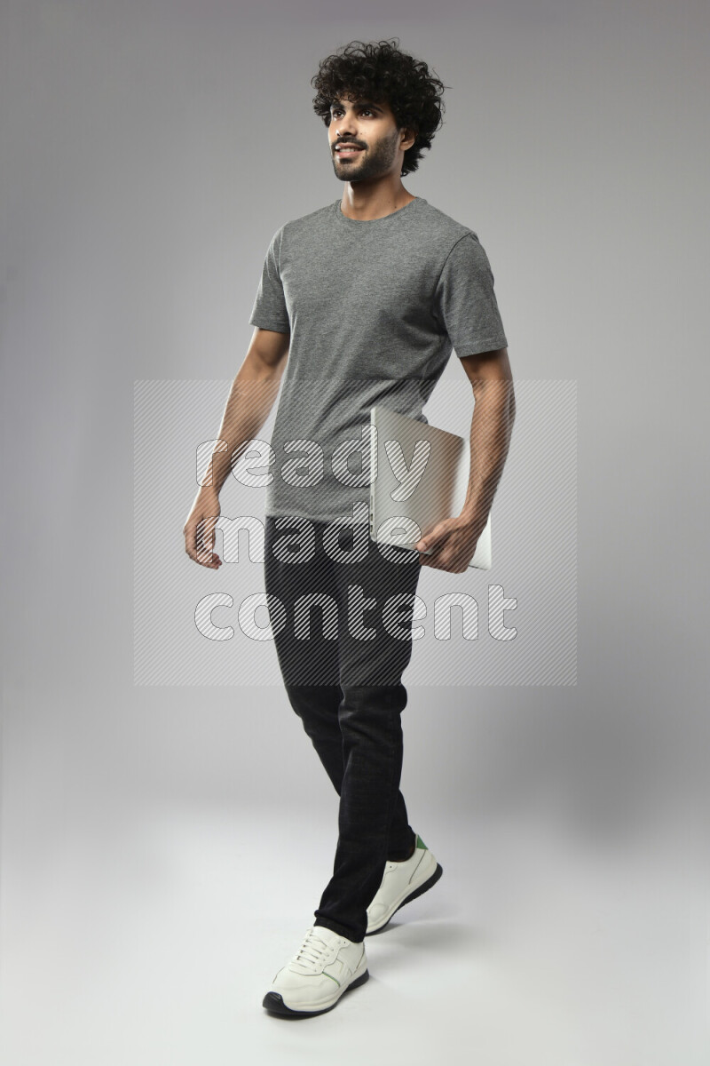 رجل يرتدي ملابس كاجوال يحمل لاب توب علي خلفية بيضاء