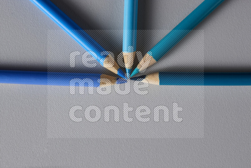 An arrangement of colored pencils in different colors on grey background