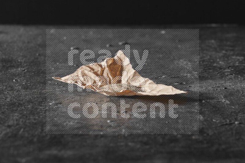 Black pepper powder on crumpled paper on a textured black flooring