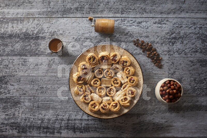 Oriental sweets in a pottery plate with nuts, coffee and honey in a dark setup