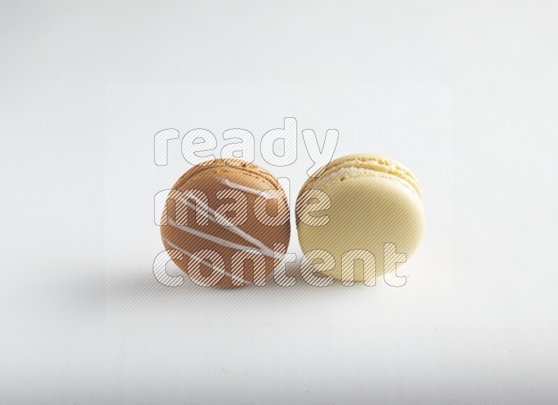 45º Shot of of two assorted Brown Irish Cream, and Yellow Vanilla macarons on white background