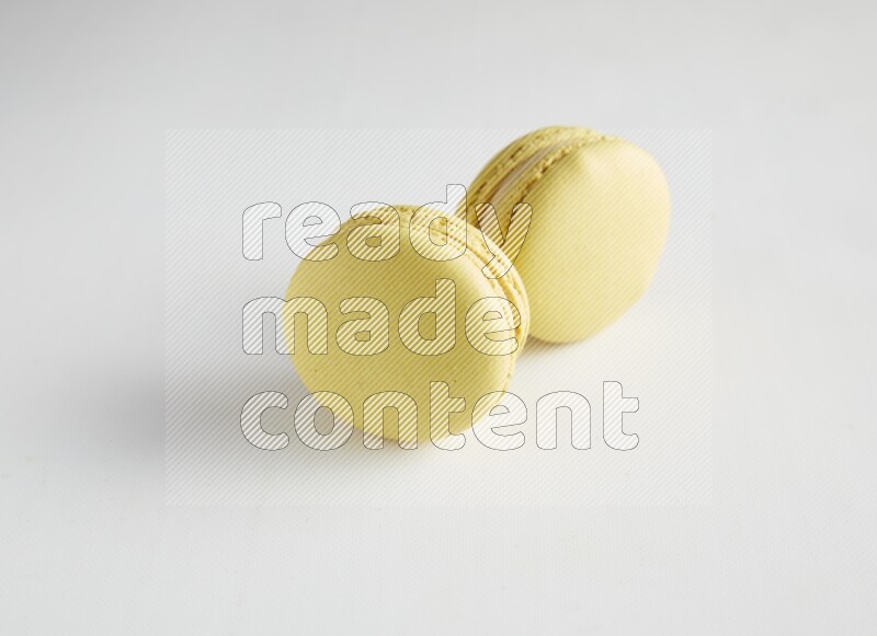 45º Shot of two Yellow Lime macarons on white background