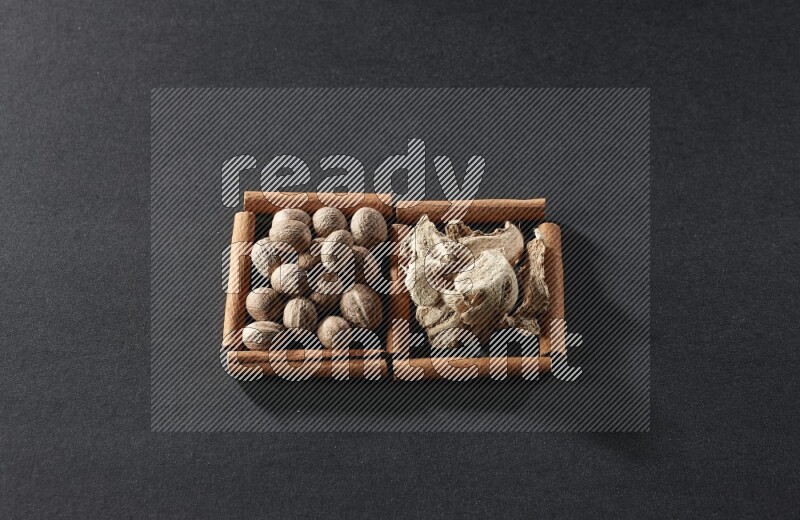 2 squares of cinnamon sticks full of nutmeg and dried ginger on black flooring