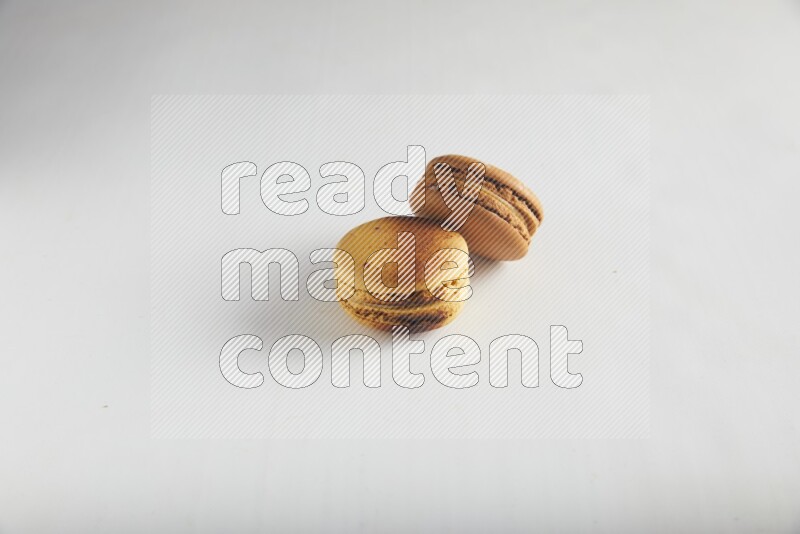 45º Shot of of two assorted Brown Irish Cream, and Yellow Crème Brulée macarons on white background
