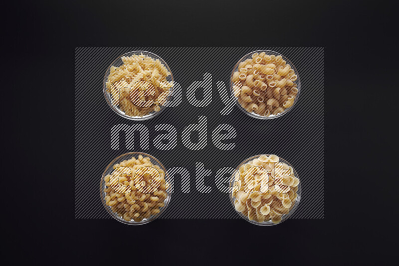 أنواع مختلفة من المعكرونة في وعاء زجاجي علي خلفية سوداء