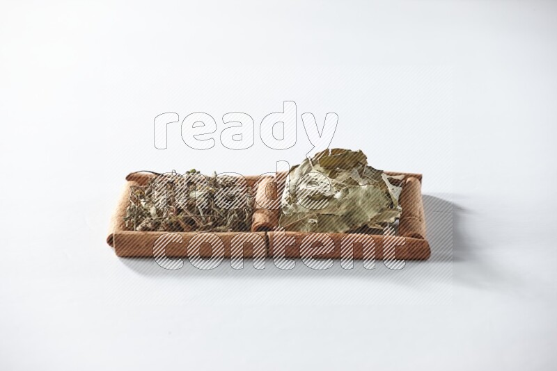 2 squares of cinnamon sticks full of dried basil and bay laurel leaves on white flooring