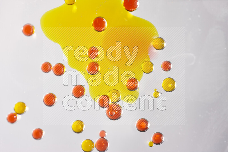 Close-ups of abstract yellow and red watercolor drops on oil Surface on white background