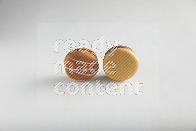 45º Shot of of two assorted Brown Irish Cream, and Yellow, and Brown Chai Latte macarons on white background