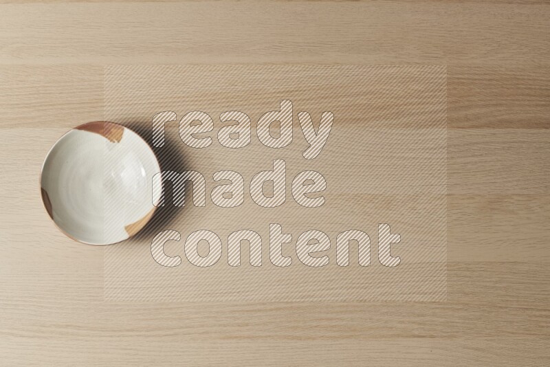 A multicolored pottery plate on light wooden background