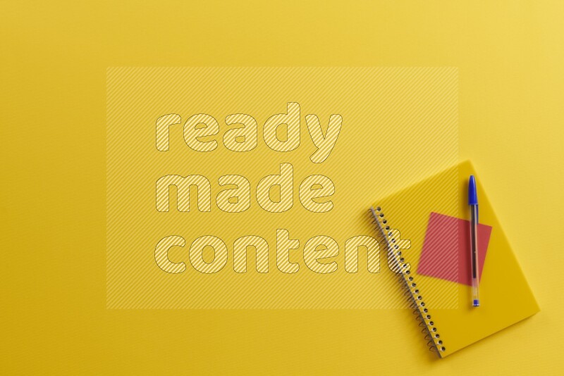 A yellow notebook with different school supplies on yellow background