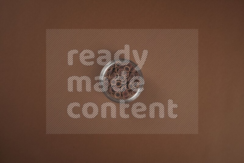 Brown buttons in a glass bowl on brown background